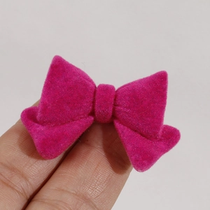 Detailed view of magenta flocked bow accessory texture held between fingers