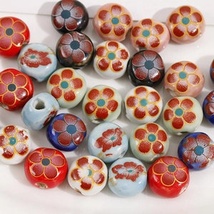 Detailed macro view of 12mm double-sided floral ceramic beads with golden outlines for DIY