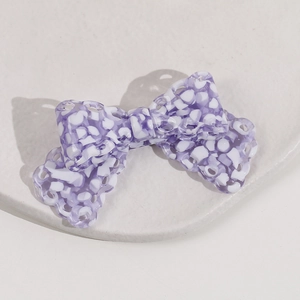 Macro detail of purple and white floral pattern on a large acetate bow hair clip accessory