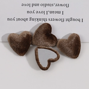 Close-up of four brown velvet heart buttons with metal backing for DIY fashion sewing