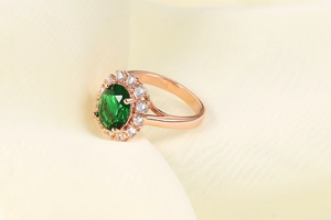 Macro di anello in oro rosa con grande smeraldo verde ovale e contorno di zirconi AAA