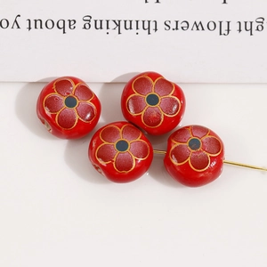 Macro shot of 12mm red floral ceramic beads with hand-painted gold detail for DIY jewelry