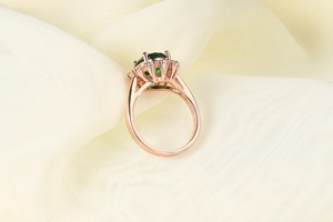 Dettaglio anello con zircone verde smeraldo placcato oro rosa con marchio S925 e halo