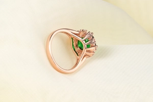 Dettaglio macro dell'anello in oro rosa con gemma verde smeraldo e piccoli zirconi