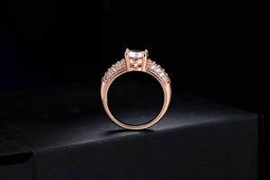 Gros plan d'une bague de fiançailles en or rose avec pierre ronde et pavage de zircons