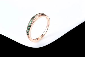 Details des roségoldenen Rings mit asymmetrischem Band und grünen Zirkon-Steinen
