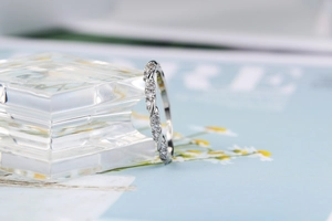 Makroaufnahme eines silberfarbenen Rings mit verdrehtem Band und Pavé-Zirkonia-Besatz