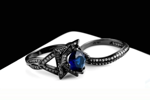 Detail van de dubbellaagse zwartgouden ringenset met ovale blauwe saffier en zirkoon