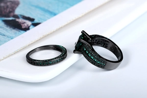 Macro detail of dual-layer black gold rings featuring emerald cut green zircon stones