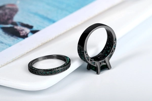 Macro shot of black gold double ring set with emerald cut green zircon and micro pave gems