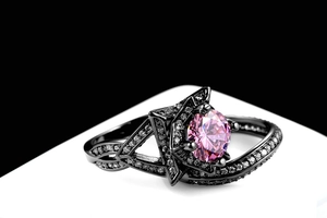 Makro-Detail eines schwarzen Rings mit rundem rosa Stein und weißen Pavé-Diamanten