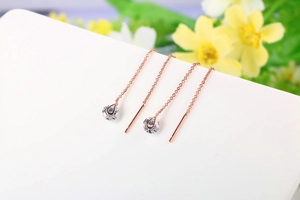 Dettaglio degli orecchini a catenella in oro rosa con pendenti in cristallo trasparente