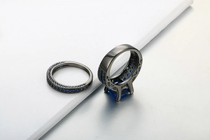 Detail of double-layer black gold rings featuring a square blue zircon and pavé settings