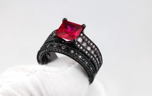 Macro shot of black gold ring set with large square red gemstone and pavé accents