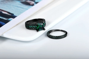 Detail of black gold ring set with emerald green princess cut zircon and micro pave band