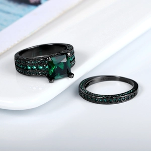 Elegant black gold ring set featuring square green zircon main stone on white ceramic tray