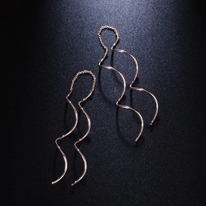Eleganti orecchini a onda in oro rosa con catenine sottili su sfondo scuro strutturato