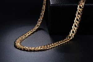 Macro-opname van 18K vergulde Cubaanse schakelketting met spiegelglans op zwart leer