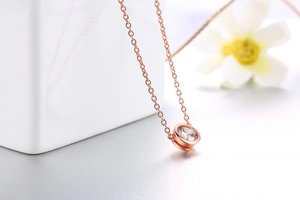 Dettaglio di una collana in oro rosa con un ciondolo tondo in zircone scintillante