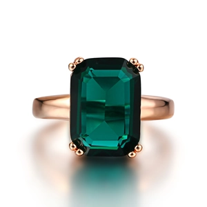 Close-up of a large emerald-cut green gemstone ring with a rose gold plated band and reflection