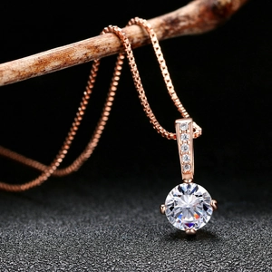 Elegant rose gold necklace with a round-cut solitaire zircon pendant on a wooden branch
