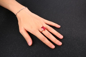 Detailed view of rectangle cut ruby ring in rose gold finish on hand with bracelet