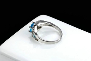 Detail of blue zircon ring with silver cross band and sparkling brown stones