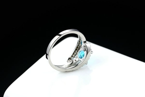 Macro view of blue zircon ring with intricate hollowed layers and polished silver finish