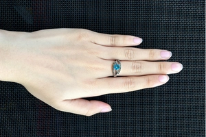 Close-up of blue sapphire ring with black diamond accents worn on a female finger