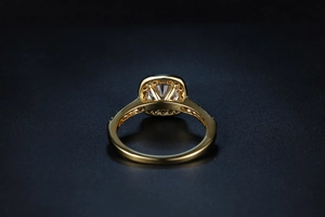 Detail of square-cut sparkling gemstone ring with halo setting and gold plating