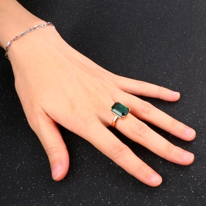 Elegant emerald-cut green gemstone ring in rose gold setting worn by a model
