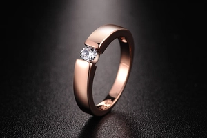 Detail of rose gold engagement ring showing round brilliant diamond and 18K hallmark