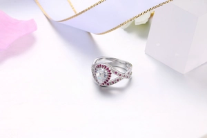 Dettaglio anello a goccia con alone rosa e fascia incrociata in argento su seta