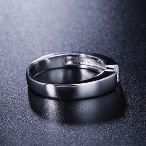 Minimalist silver engagement ring with single diamond on black reflective background