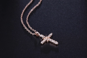 Dettaglio macro del ciondolo a croce in oro rosa con zirconi pavé e motivo a stella
