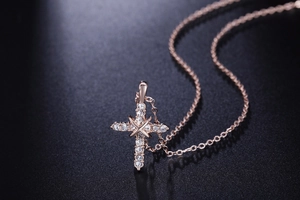 Dettaglio macro della collana con ciondolo a croce in oro rosa e zirconi su nero