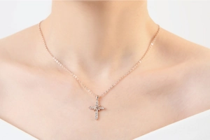 Primo piano di una collana a croce in oro rosa con zirconi indossata da una modella