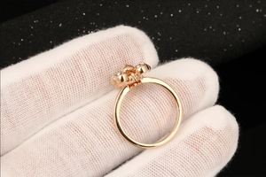 Detail van een roségouden bloemring met zirkonia steentjes vastgehouden met handschoen