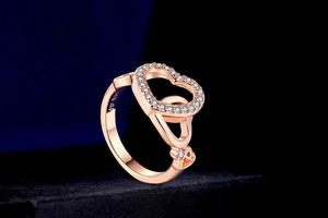 Macro shot of 18K GP rose gold ring featuring interlocking hearts and sparkling zircon stones