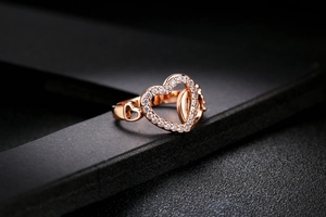Macro detail of rose gold heart ring featuring pave-set cubic zirconia on a dark surface