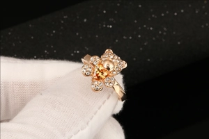 Detailopname van een roségouden berenring met gele hartvormige zirkoon en witte stenen