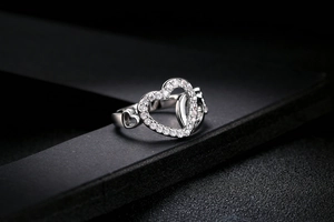 Detail of interlocking heart ring featuring shimmering cubic zirconia on dark texture