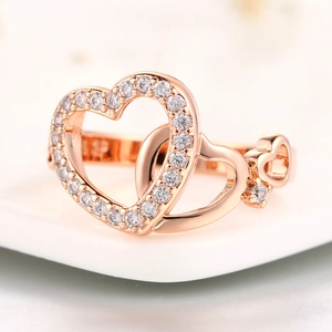 Rose gold interlocking heart ring with sparkling cubic zirconia on a white ceramic tray