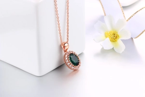 Dettaglio della collana in oro rosa con ciondolo in cristallo smeraldo ovale e zirconi bianchi
