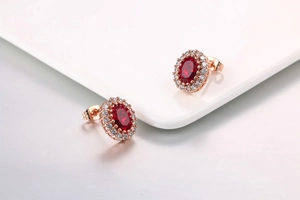 Dettaglio di orecchini oro rosa con cristalli rossi ovali e pavé di piccoli diamanti