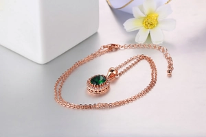 Dettaglio della collana in oro rosa con ciondolo smeraldo ovale e chiusura a moschettone