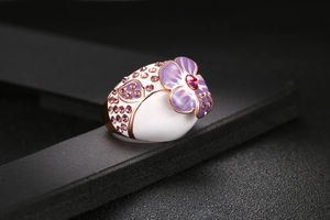 Detailaufnahme des vergoldeten Pflaumenblütenrings mit Lavendel-Emaille und pinkem Kristall