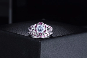 Macro-detail van zilveren ringenset met heldere steen en roze halo in zwarte juwelendoos