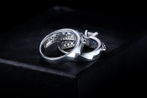 Macro detail of blue and white zircon micro-pave wedding rings set on black texture box