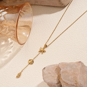 Boheemse gouden ketting met zeester en schelp hangers op een getextureerde achtergrond